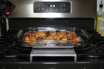 Baked teriayki chicken wings from the oven resting on the stove top in a home kitchen.
