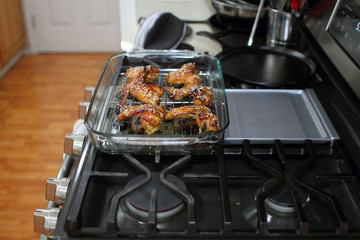Baked teriayki chicken wings from the oven resting on the stove top in a home kitchen.