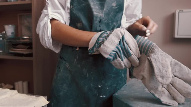 potter preparing the pottery kiln for the baking process for her dish. professional potter puting her raw clay dish into kiln to bake and harden. Potter baking a dish in the kiln to harden the clay.