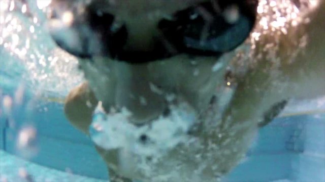 Person swimming in a olympic pool, frontal shot.