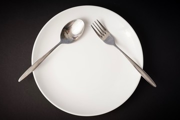 Healthy eating concept: white plate with fork and spoon