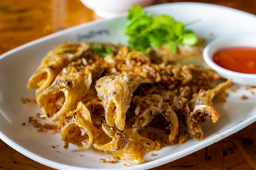 Closed up deep fried Thai style river fish (Sheatfish Fried) “Par Nae Non”, Traditional Thai Food with fried chopped garlic. Serverd with source. Delicious and yummy.
