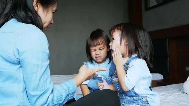 Mother and her daughter playing together in the bedroom. The child having fun to play rock-paper-scissors on the bed. Family relaxation time in vacation day.
