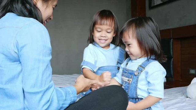 Mother and her daughter playing together in the bedroom. The child having fun to play rock-paper-scissors on the bed. Family relaxation time in vacation day.