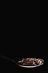 beverage background of roasted coffee beans in spoon isolated on dark background
