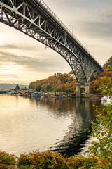 Fototapeta na wymiar A bridge spans across a lake as fall colors show off in the trees