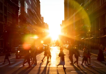 Foto op Canvas Mensen lopen aan de overkant van de straat in New York City met het heldere licht van de zonsondergang tussen de gebouwen langs de 23e St in Midtown Manhattan © deberarr