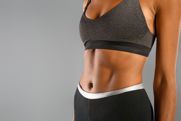 Sporty young African-American woman on grey background, closeup