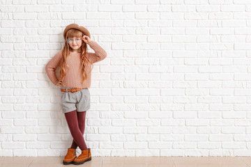 Cute fashionable girl on near white brick wall
