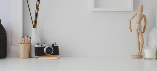 Minimal workspace with copy space, camera and office supplies on white desk and white wall