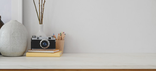 Minimal workspace with copy space, camera and office supplies on white desk and white wall