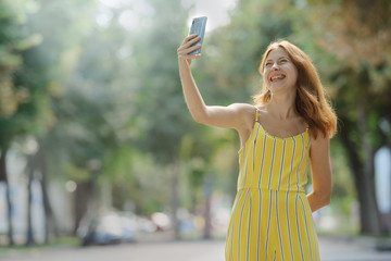 Young smart smiling girl taking a selfie with her cell phone.