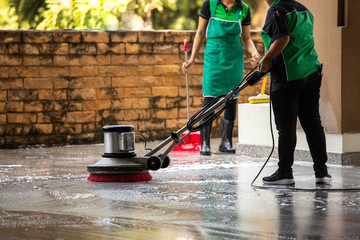 The worker cleaning floor exterior walkway using polishing machine and chemical or acid