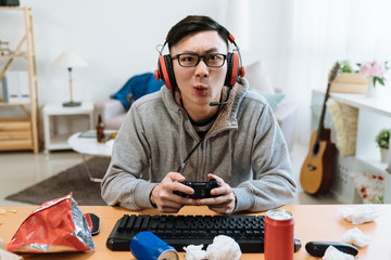 Nerd geek young adult man playing on video console enjoy online game. asian male gamer concentrated...