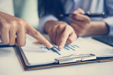 Close up of  business co-worker hand pointing at business document during discussion at meeting. businessman and businesswoman discussing information at the office.