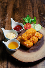 Crispy salmon cheese placed on a wooden chopping board with three dipping sauces, mayonnaise, tomato sauce, chicken sauce