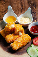  Crispy salmon cheese placed on a wooden chopping board with three dipping sauces, mayonnaise, tomato sauce, chicken sauce