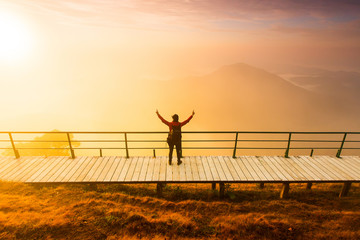 Silhouette of man hold up hands on the peak of mountain,success concept