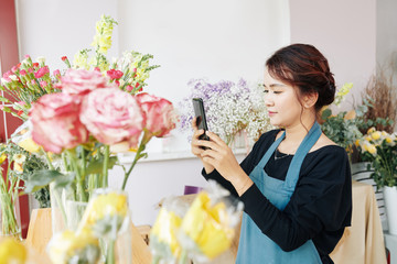 Young Vietnamese florist posing photos of finished bouquets on social media