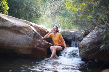 Fototapeta na wymiar A woman playing in the Khao Banchop waterfall, Chanthaburi, Thailand