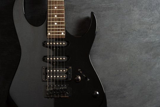 Black electric guitar on black cement floor. Top view and copy space for text. Concept of rock music.