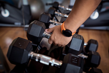Fototapeta na wymiar hand with a smart watch lift a dumbbell from roll of sumbbells