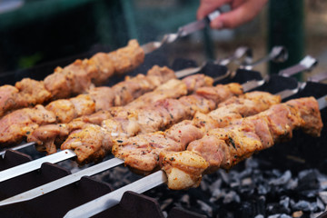 Shish kebab roasting on the grill. BBQ party. Close-up. Marinated shashlik preparing on a barbecue grill over charcoal.