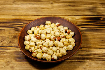 Peeled hazelnuts in ceramic plate on wooden table