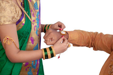 Girl tying a rakhi on her brothers hand - Image