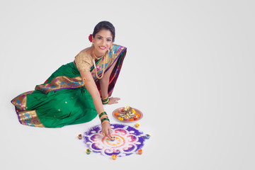 Portrait of Maharashtrian girl celebrating festival with rangoli & oil lamps  - Image