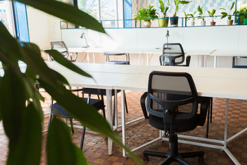 Loft style office with white brick walls and concrete columns. There is a meeting area with a large white table with black chairs