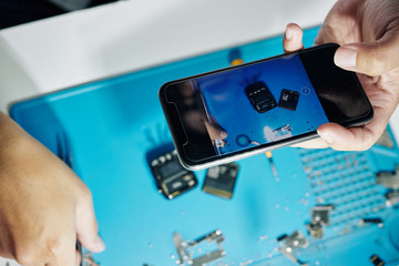 Repairman taking photo of disassembled smartwatch to depict details positions