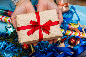 hands in a knitted sweater holding gift present box. Christmas holidays preparation concept.