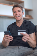 smiling man makes an online purchase sitting on the couch
