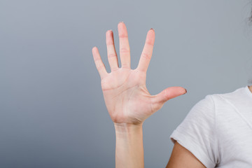 female hand in fist showing five fingers isolated over grey