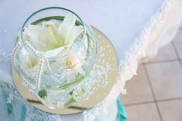 Wedding table decoration in a restaurant - glass sphere with white flowers, pearls and lace - selective focus