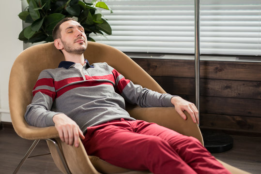 The young man relaxes, lies in a chair with his eyes closed