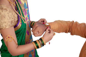 Girl tying a rakhi on her brothers hand - Image