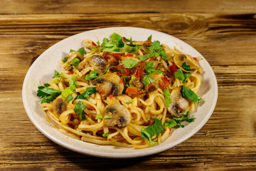 Pasta with mushrooms and tomato sauce on wooden table