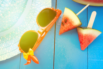 Watermelon and black glasses in the blue table on blue hat background,