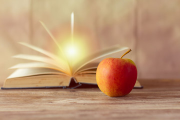 Red apple on blurred a book retro wall background,