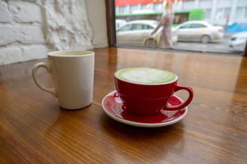 couple of cups with coffee and matcha tea on a vintage wooden table in a coffee shop