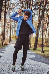 Fototapeta premium Attractive sportive student is doing stretching in the park at the morning.