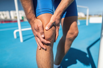 Knee pain professional athlete sport injury - sports running knee acciden on man runner. Sprained knee joint, arthritis. Closeup of legs, muscle and knee outdoors. - obrazy, fototapety, plakaty
