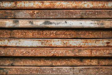 Racks of metal profiles. Metal is stored in an open warehouse. Wet and rusty on the street. Old grunge background made of rusty iron for shooting flatleys on the table. Copy space