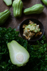 Fresh chayote fruits (Sechium edulis) stir fried with egg and garlic in bowl on wood background