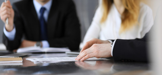 Business people or lawyers discussing questions of contract at meeting in modern office, close-up. Unknown businessman and woman with colleague sitting and working at the glass desk. Teamwork and