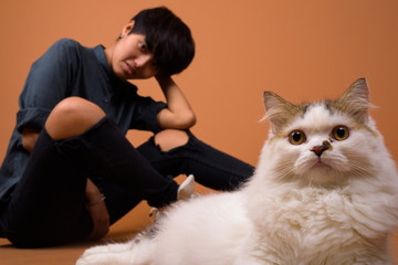 Young beautiful Asian woman with short hair against brown backgr