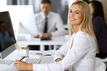 Business woman using computer at workplace in modern office. Secretary or female lawyer smiling and looks happy. Working for pleasure and success