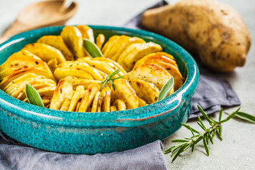 Baked white sweet potato casserole with herbs in blue dish. Healthy vegan food concept.